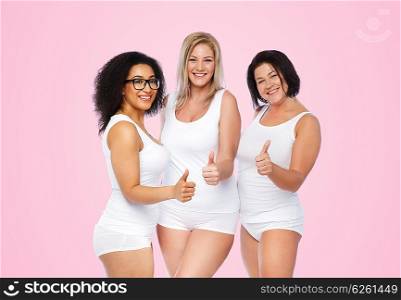 gesture, friendship, beauty, body positive and people concept - group of happy plus size women in white underwear showing thumbs up over pink background