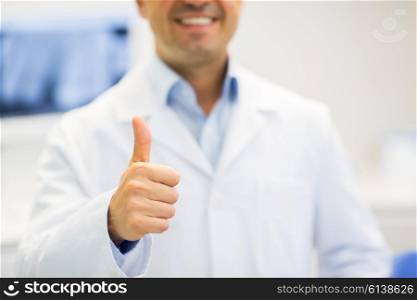 gesture, health care, people and medicine concept - close up of happy male doctor showing thumbs up at hospital