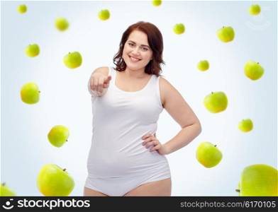 gesture, healthy eating, diet, weight loss and people concept - smiling young plus size woman in underwear pointing on you over green apples background