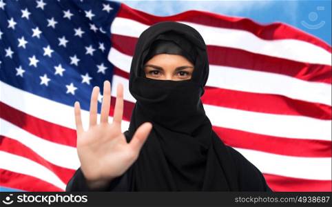 gesture, immigration, religious prohibition and people concept - muslim woman in hijab showing stop sign over american flag background. muslim woman in hijab showing stop sign