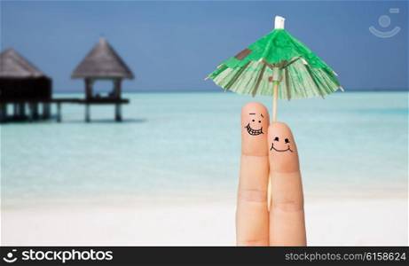 gesture, love, holidays, summer vacation and body parts concept - close up of two fingers with cocktail umbrella decoration