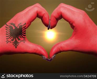 Gesture made by albania flag colored hands showing symbol of heart and love during sunrise