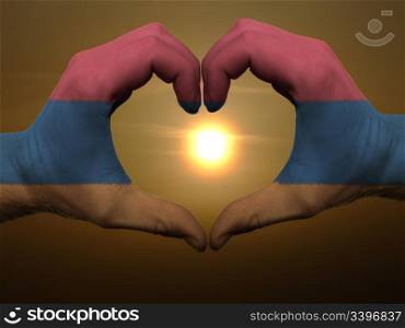 Gesture made by armenia flag colored hands showing symbol of heart and love during sunrise
