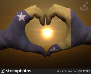 Gesture made by bosnia herzegovina flag colored hands showing symbol of heart and love during sunrise