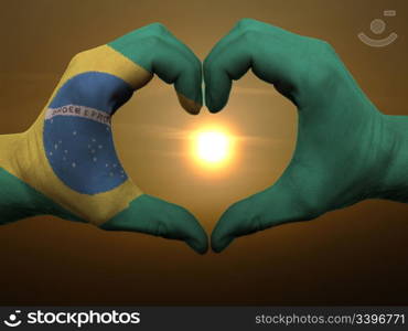 Gesture made by brazil flag colored hands showing symbol of heart and love during sunrise