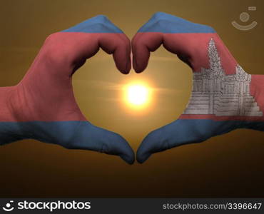 Gesture made by cambodia flag colored hands showing symbol of heart and love during sunrise