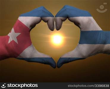 Gesture made by cuba flag colored hands showing symbol of heart and love during sunrise