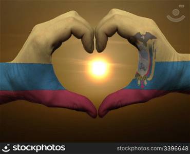 Gesture made by ecuador flag colored hands showing symbol of heart and love during sunrise