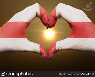 Gesture made by england flag colored hands showing symbol of heart and love during sunrise