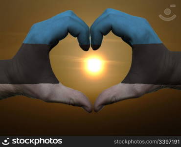 Gesture made by estonia flag colored hands showing symbol of heart and love during sunrise