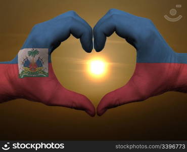 Gesture made by haiti flag colored hands showing symbol of heart and love during sunrise