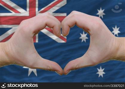 Gesture made by hands showing symbol of heart and love over australian flag