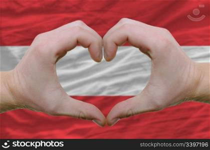 Gesture made by hands showing symbol of heart and love over austrian flag