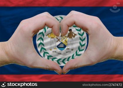 Gesture made by hands showing symbol of heart and love over belize flag