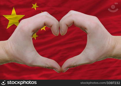 Gesture made by hands showing symbol of heart and love over china flag