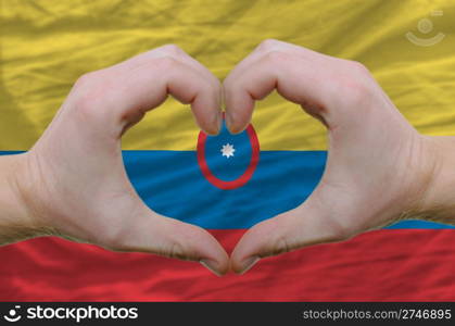 Gesture made by hands showing symbol of heart and love over columbia flag