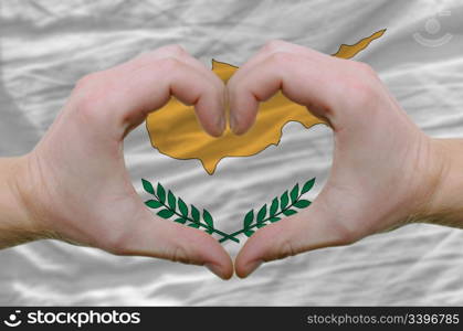 Gesture made by hands showing symbol of heart and love over cyprus flag