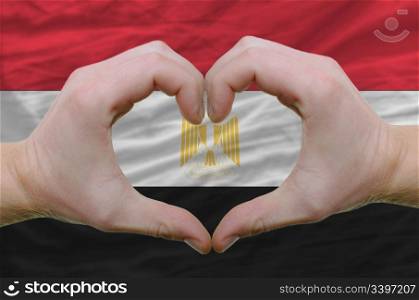 Gesture made by hands showing symbol of heart and love over egypt flag
