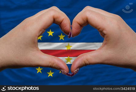Gesture made by hands showing symbol of heart and love over flag of cape verde