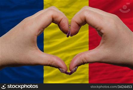 Gesture made by hands showing symbol of heart and love over flag of chad