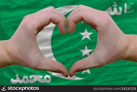 Gesture made by hands showing symbol of heart and love over flag of comoros