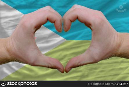 Gesture made by hands showing symbol of heart and love over flag of djibuti