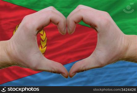 Gesture made by hands showing symbol of heart and love over flag of eritrea