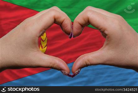 Gesture made by hands showing symbol of heart and love over flag of eritrea