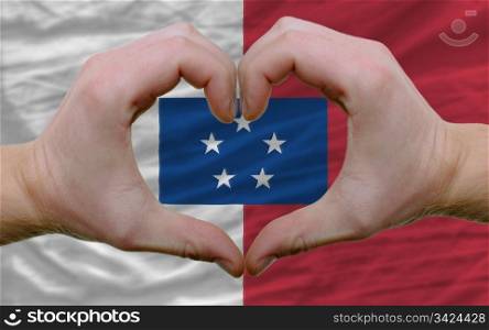 Gesture made by hands showing symbol of heart and love over flag of franceville