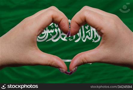 Gesture made by hands showing symbol of heart and love over flag of saudi arabia