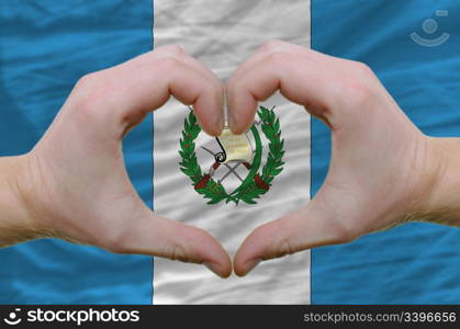 Gesture made by hands showing symbol of heart and love over guatemala flag