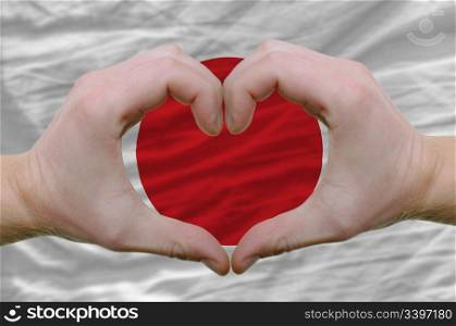 Gesture made by hands showing symbol of heart and love over japan flag