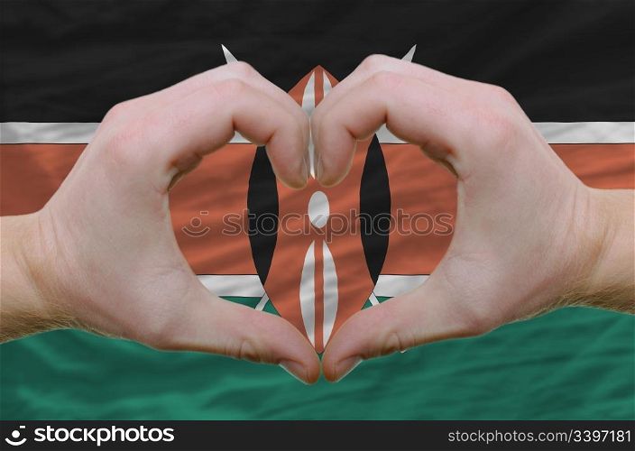 Gesture made by hands showing symbol of heart and love over kenya flag
