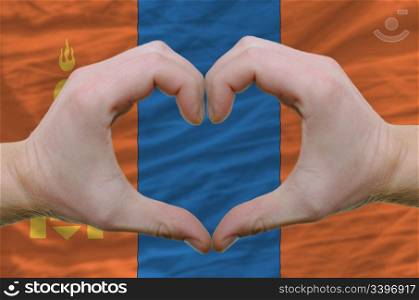 Gesture made by hands showing symbol of heart and love over mongolia flag