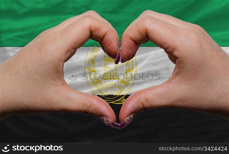 Gesture made by hands showing symbol of heart and love over national afghanistan flag