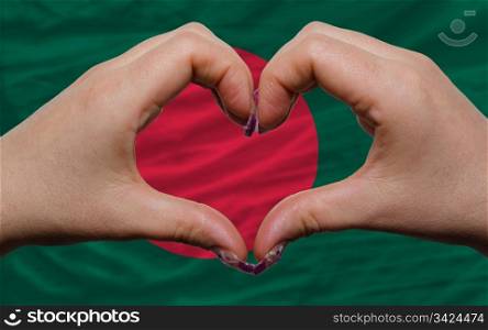 Gesture made by hands showing symbol of heart and love over national bangladesh flag