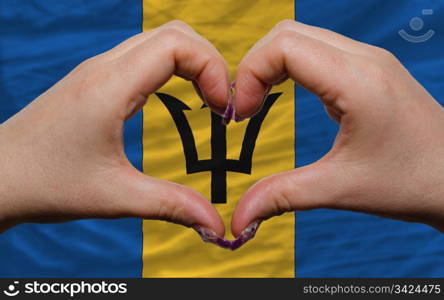 Gesture made by hands showing symbol of heart and love over national barbados flag