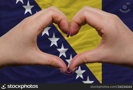 Gesture made by hands showing symbol of heart and love over national bosnia herzegovina flag