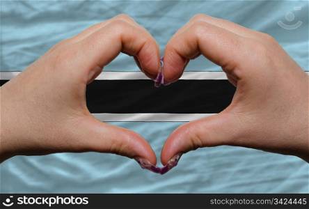 Gesture made by hands showing symbol of heart and love over national botswana flag