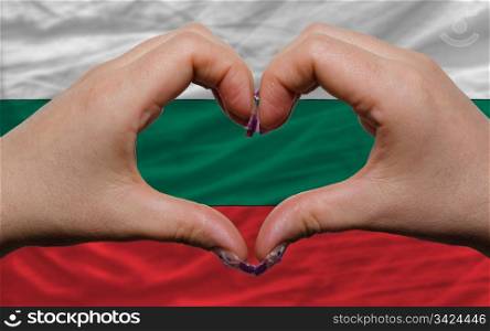 Gesture made by hands showing symbol of heart and love over national bulgaria flag