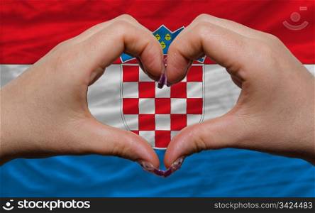 Gesture made by hands showing symbol of heart and love over national croatia flag