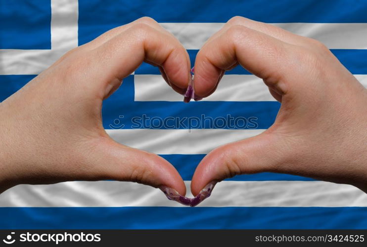 Gesture made by hands showing symbol of heart and love over national greece flag