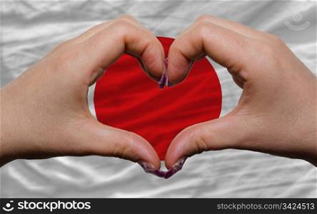Gesture made by hands showing symbol of heart and love over national japan flag