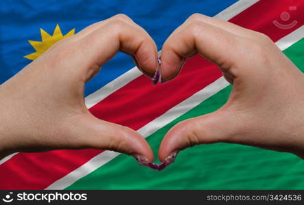 Gesture made by hands showing symbol of heart and love over national namibia flag
