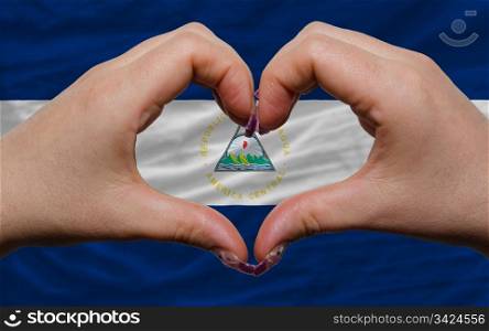 Gesture made by hands showing symbol of heart and love over national nicaragua flag