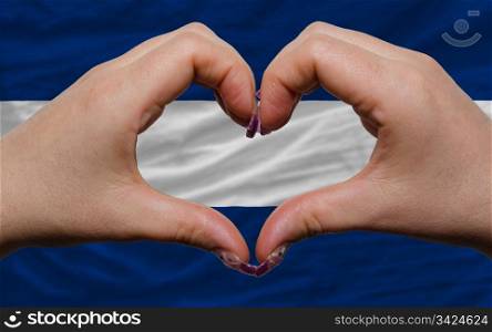 Gesture made by hands showing symbol of heart and love over national nicaragua flag