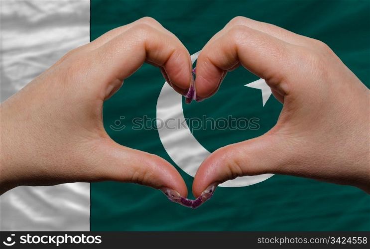 Gesture made by hands showing symbol of heart and love over national pakistan flag