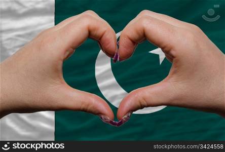 Gesture made by hands showing symbol of heart and love over national pakistan flag