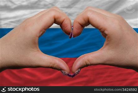 Gesture made by hands showing symbol of heart and love over national russia flag