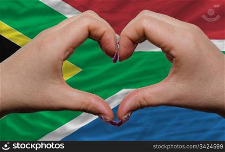 Gesture made by hands showing symbol of heart and love over national south africa flag